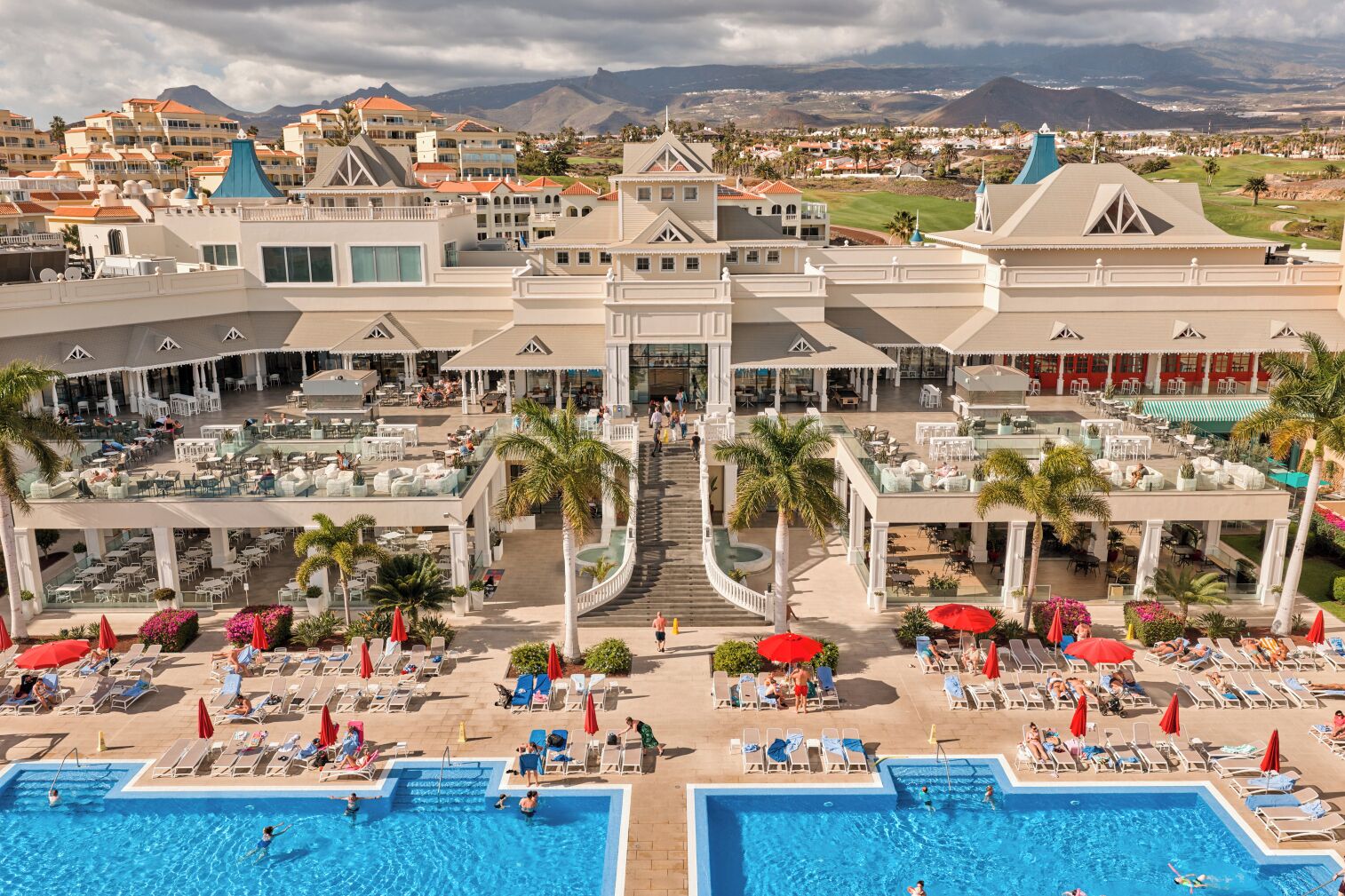 A resort with multiple swimming pools, outdoor seating areas, and a central staircase.