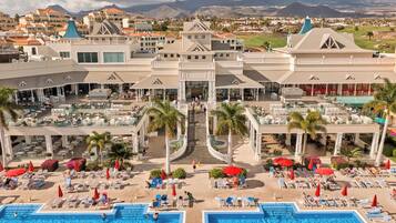 Un resort con varias piscinas, zonas de estar al aire libre y una escalera central.