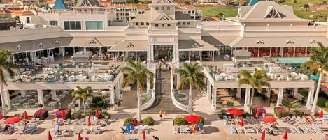 A resort with multiple swimming pools, outdoor seating areas, and a central staircase.