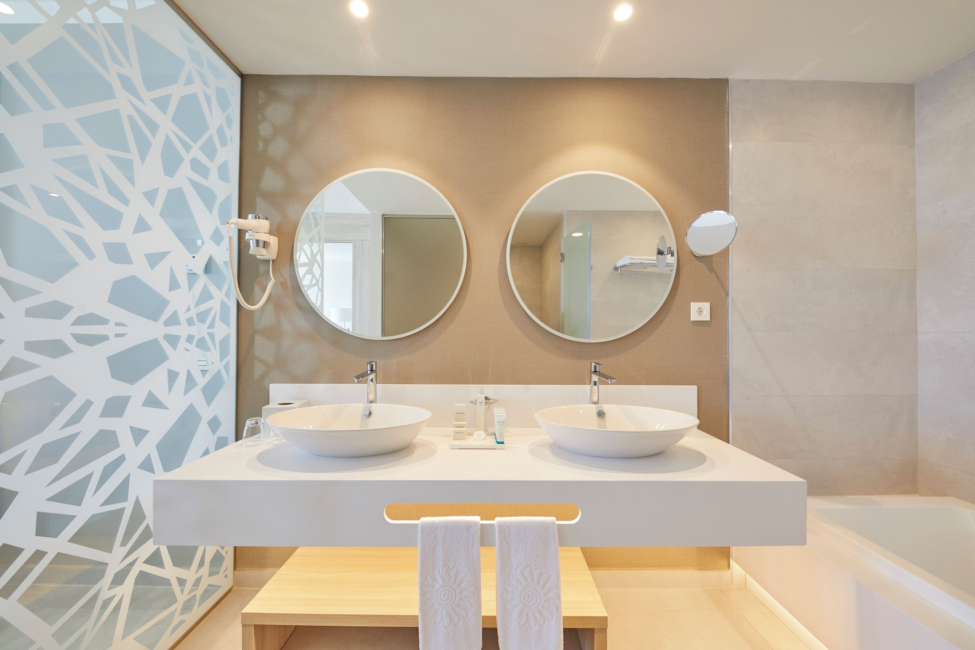 Ein modernes Badezimmer mit zwei Waschbecken, einer Badewanne und zwei Spiegeln an der Wand.