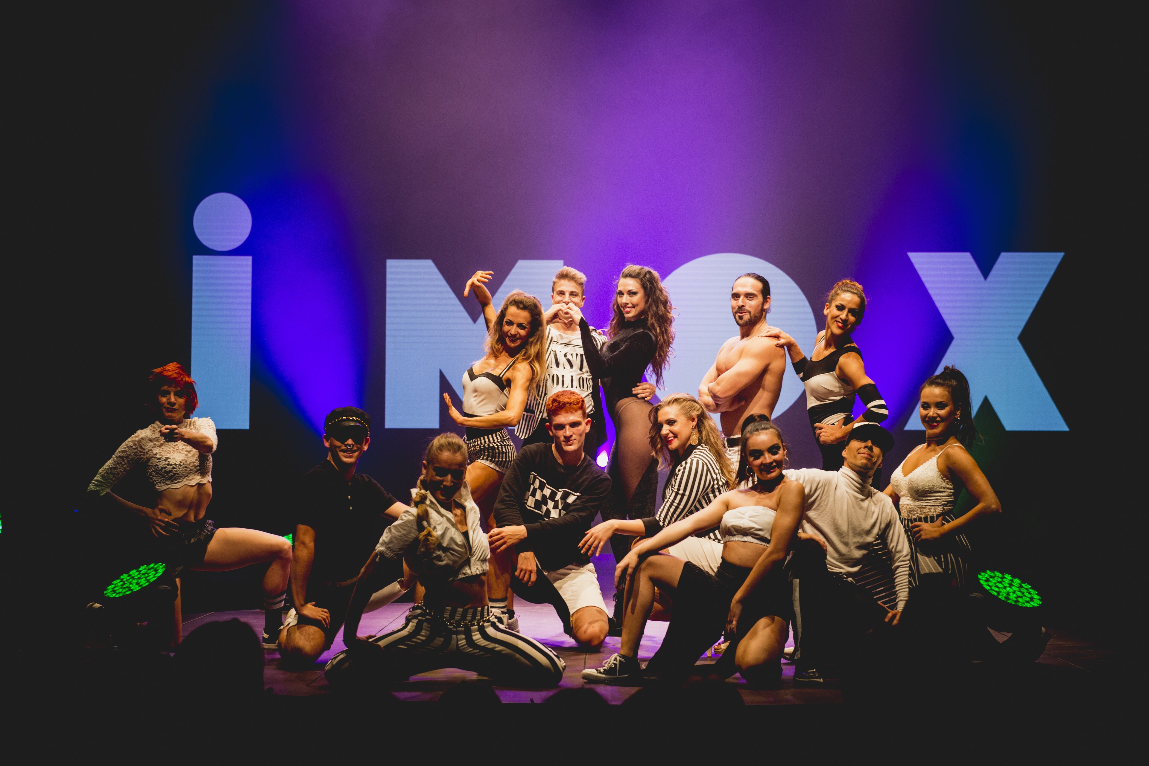 Un groupe de personnes posant sur une scène, avec une grande enseigne « iMAX » en arrière-plan.