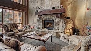 A cozy living room with a stone fireplace, comfortable seating, and a view of the outside. - Modern Ground Floor Unit/1 Minute Walk to the Gondola/Great Amenities (Keystone)