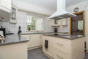 Enjoy cooking in this well-equipped kitchen with a central island, stove, and large window.