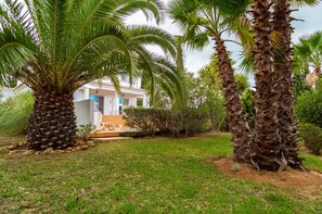 Stroll through the serene garden, surrounded by lush greenery and palm trees, to the entrance of this charming residence.