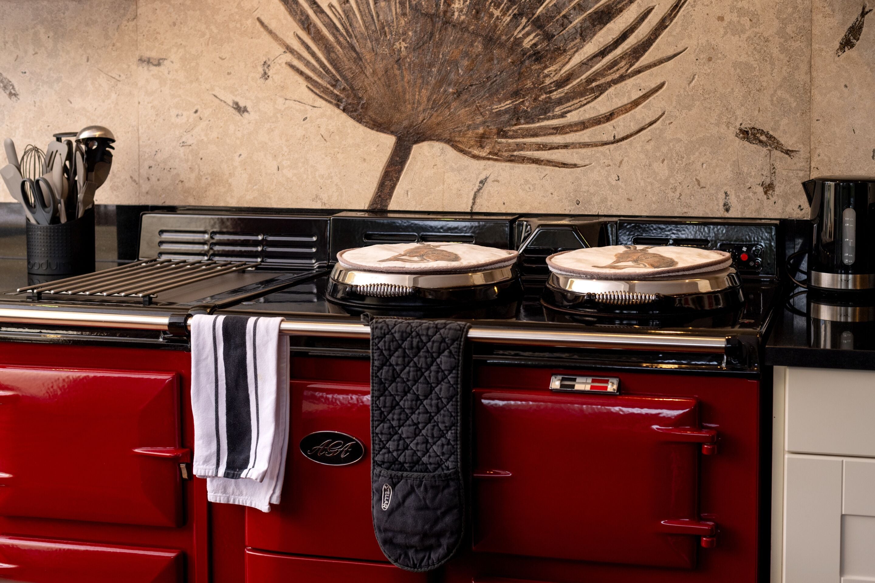 A red kitchen with two stoves, a kettle, and a knife block.