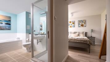 Un baño moderno con cabina de ducha de vidrio, una bañera blanca y un inodoro.