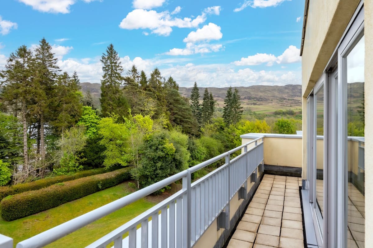 A balcony with a view of a green landscape and trees.