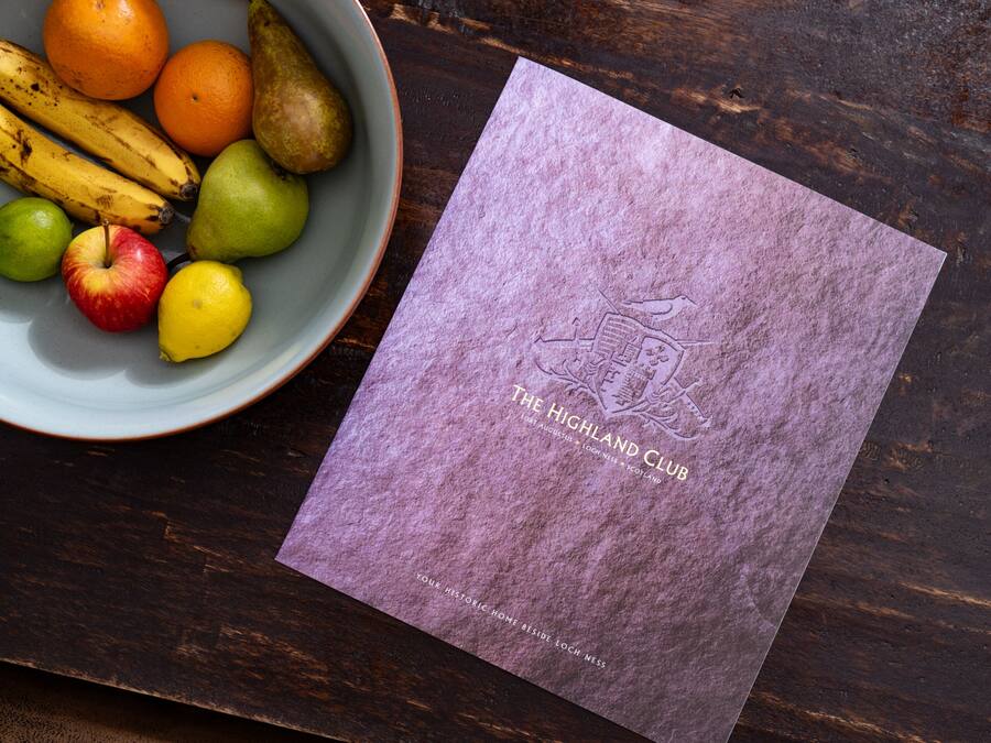 A bowl of fruit and a brochure on a wooden table.