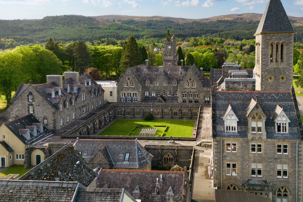 A historic building with a central courtyard, stone architecture, and a tower.