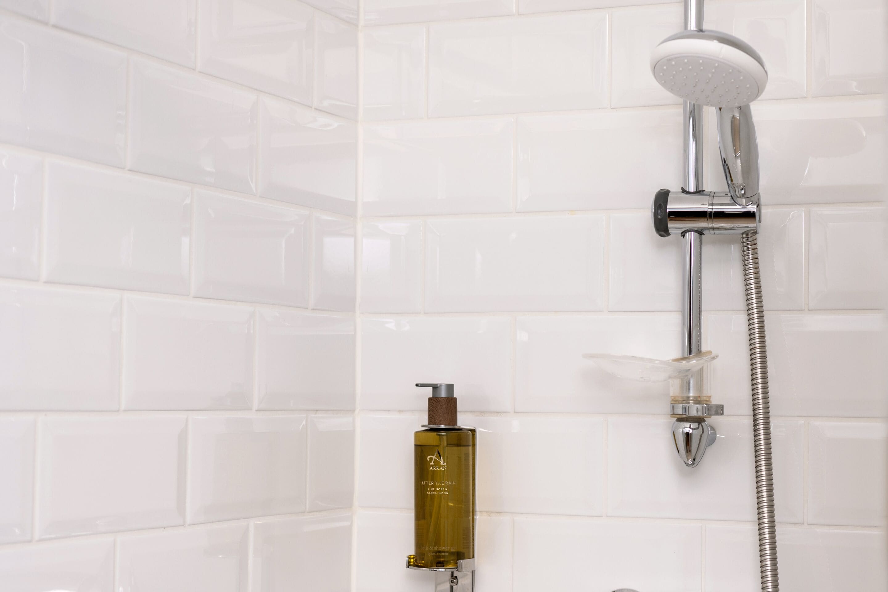 A shower with a handheld showerhead and a handheld soap dispenser.