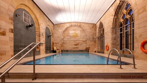 A pool area with steps leading into the water, a 'Please shower' sign, and life-saving equipment. - The Highland Club (Fort Augustus)