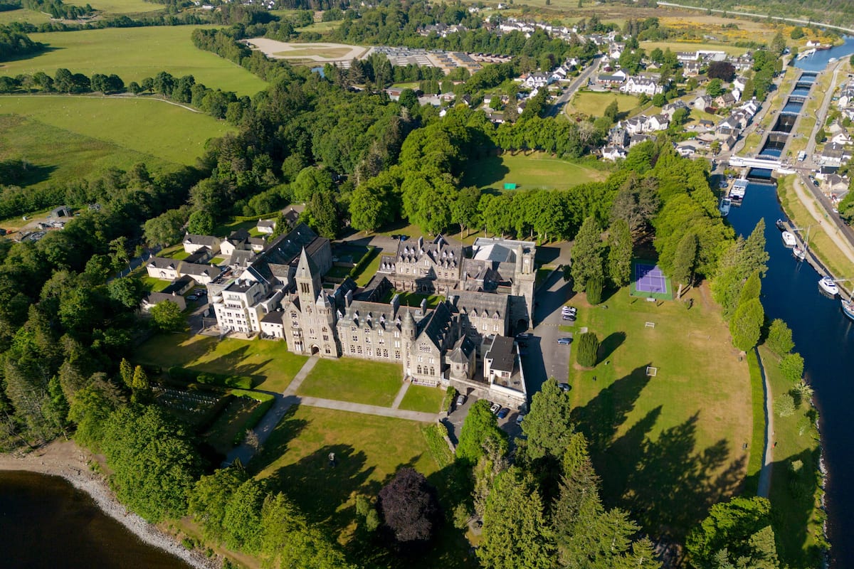 An aerial view of a historic castle surrounded by lush greenery and a river.