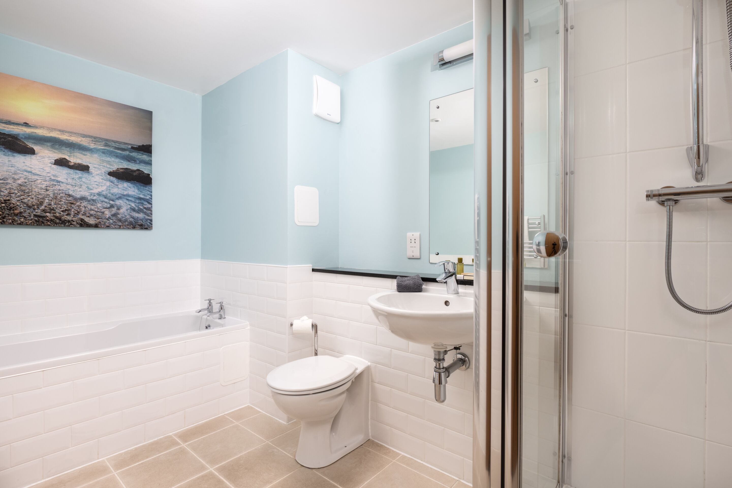 Un bagno moderno con vasca, servizi igienici, lavandino e cabina doccia in vetro.