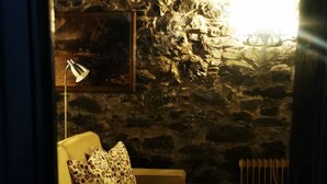 Una habitación acogedora con sofá, lámpara y pared de piedra.