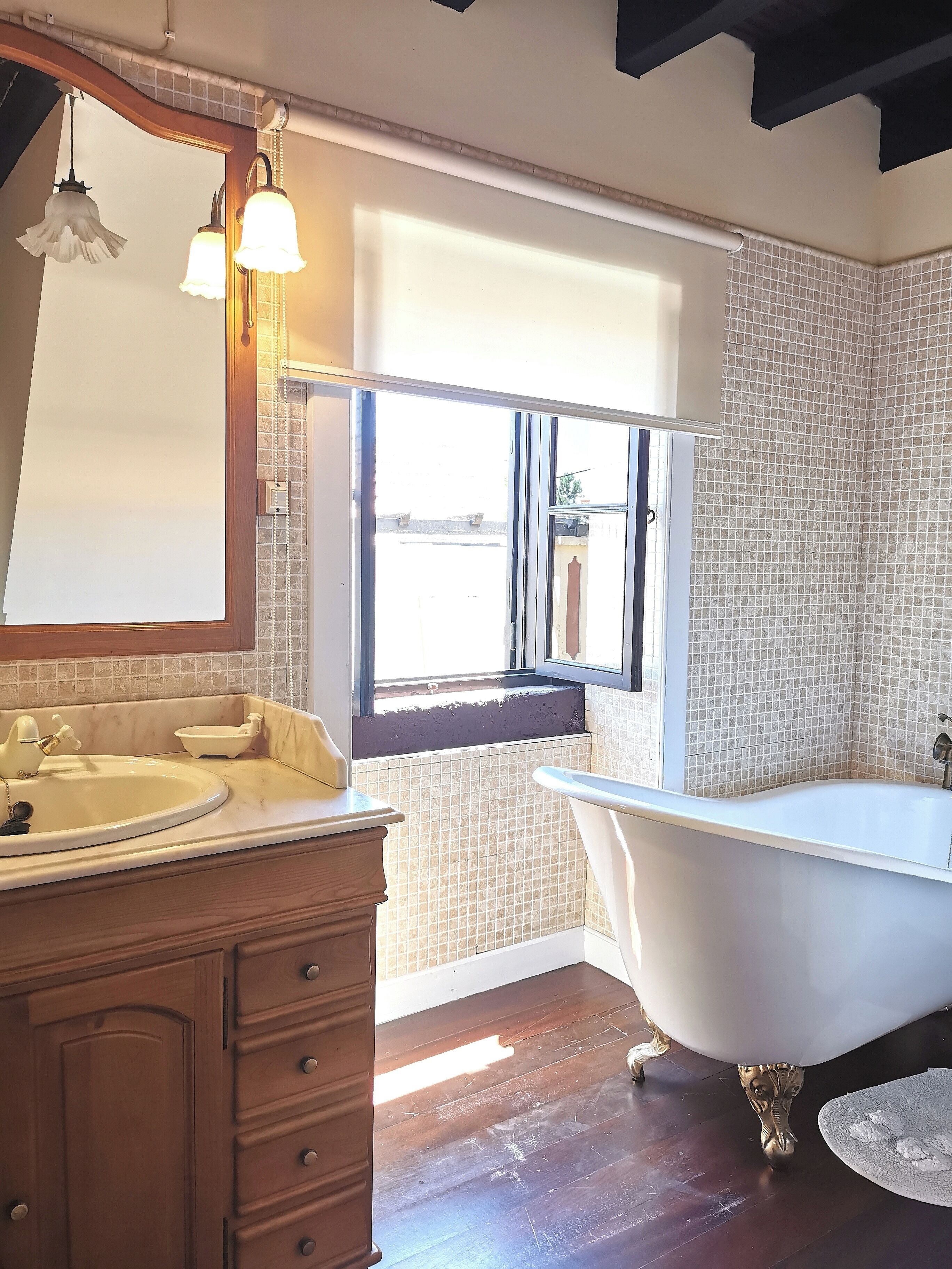 A bathroom with a freestanding bathtub, a vanity with a mirror, and a window with a view of the outside.