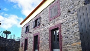 Un edificio de piedra con múltiples ventanas y una puerta, sobre un suelo adoquinado.