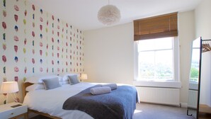 A bedroom with a large bed, a nightstand, a lamp, a radiator, and a window with a view. - Gorgeous, peaceful & very central apartment with fabulous views. (Bath)