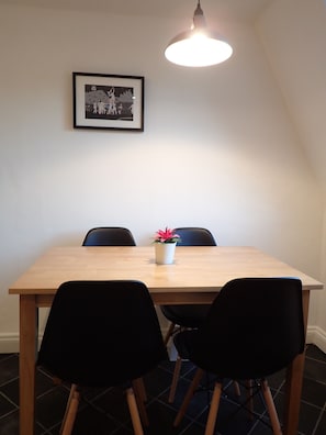 A dining area with a wooden table, black chairs, a potted plant, and a framed picture on the wall. - Gorgeous, peaceful & very central apartment with fabulous views. (Bath)