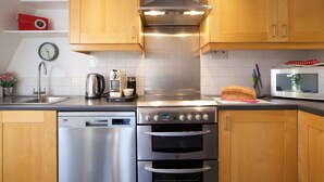 A modern kitchen with wooden cabinets, stainless steel appliances, and a clock on the wall. - Gorgeous, peaceful & very central apartment with fabulous views. (Bath)