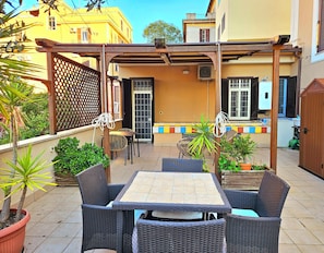 Une terrasse extérieure aménagée avec des meubles en osier, une pergola et des plantes en pot.