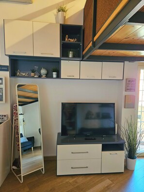 A modern living room with a flat-screen TV, white cabinets, a mirror, and a staircase. - DELICIOUS LOFT TO SAN PIETRO (Roma)