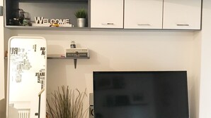 A modern living room with a flat-screen TV, white cabinetry, a small shelf with decorative items, and a potted plant. - DELICIOUS LOFT TO SAN PIETRO (Roma)