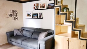 A living room with a grey sofa, wooden staircase, and wall-mounted pictures. - DELICIOUS LOFT TO SAN PIETRO (Roma)