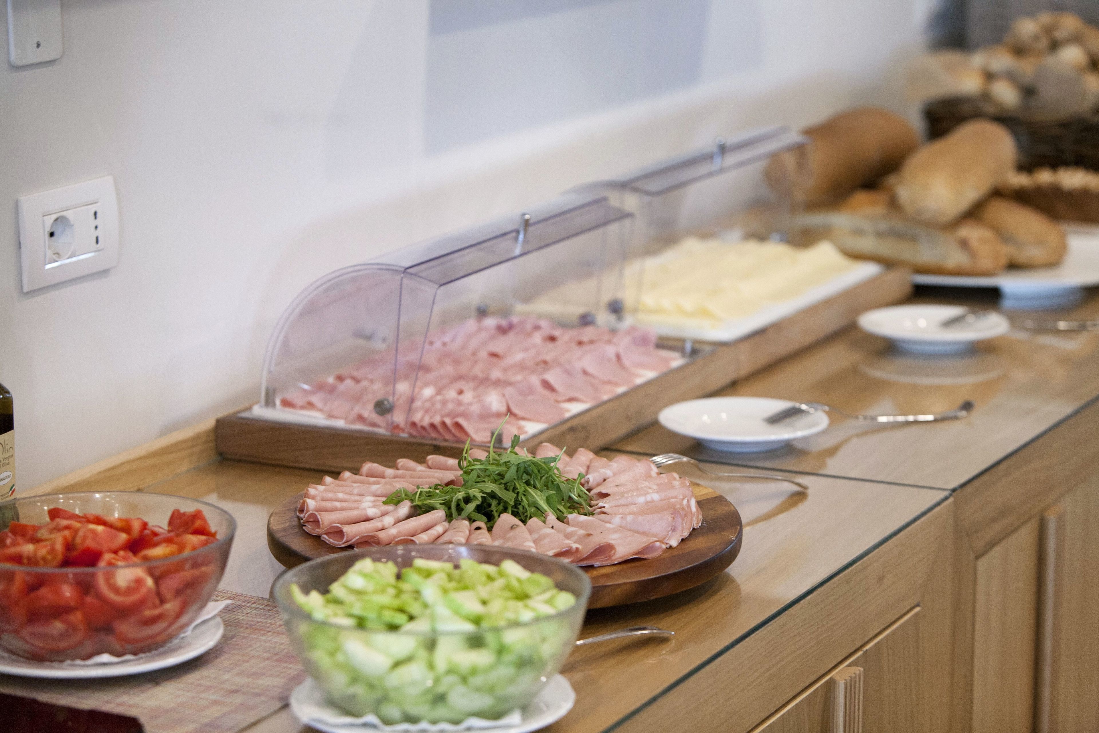 Un buffet proposant une variété d’aliments, notamment des viandes et des fromages en tranches, ainsi que des légumes.