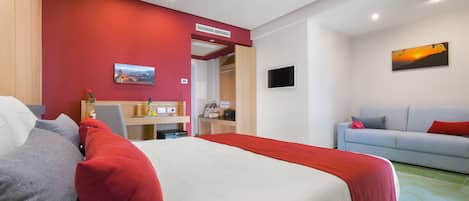 Una habitación de hotel con cama, escritorio, sofá y televisor.
