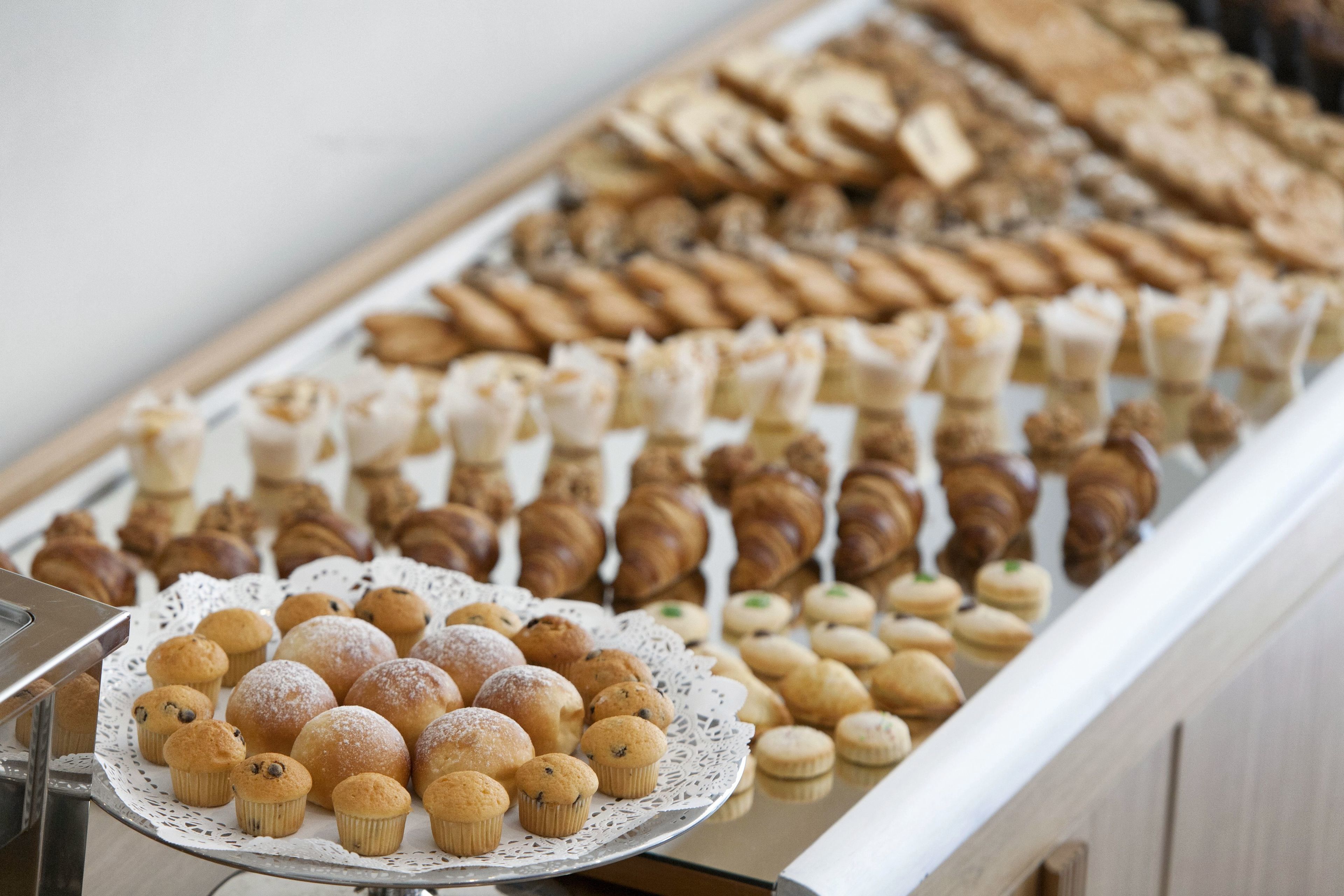 A display of assorted pastries and baked goods, including muffins, croissants, and cookies, arranged on a tray.