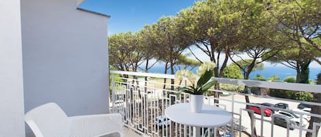 Un balcon avec une chaise blanche, une petite table ronde et un pot de fleurs.