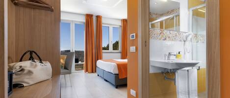 Una habitación de hotel con cama, baño y vistas al exterior.