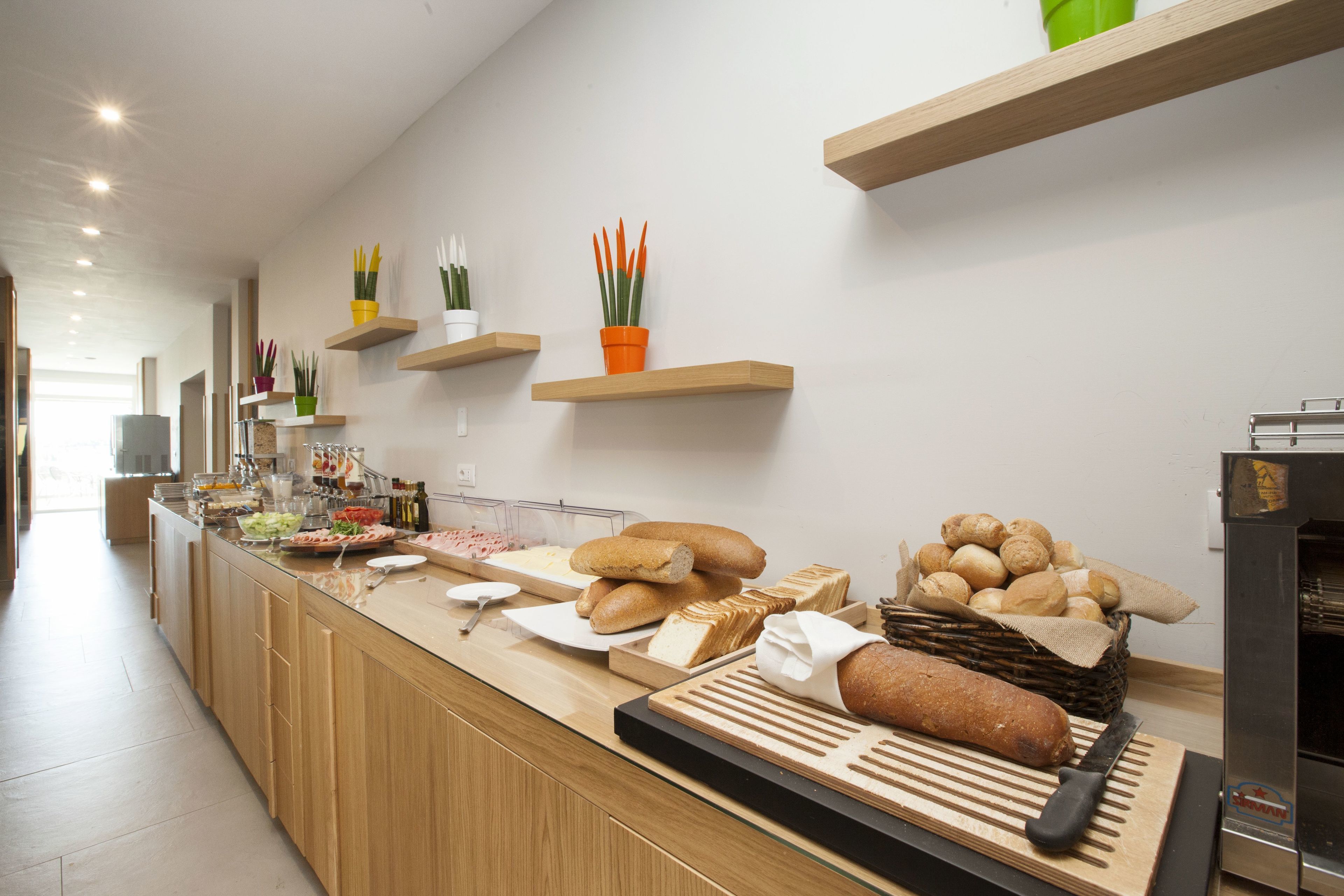 Un aparador de buffet amb diversos plats i una rebanadora de pa.