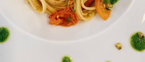 A plate of spaghetti with shrimp, garnished with herbs and a green sauce.