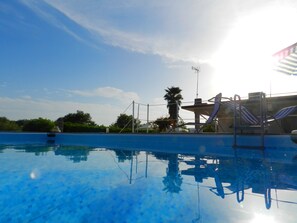 A swimming pool with clear blue water, a palm tree, and a sunshade structure. - I Colori degli Agrumi - Relaxing Villa&Piscina 12km from Syracuse - (Floridia)