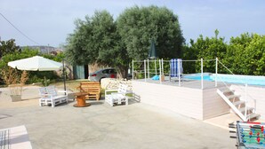 A pool area with a foosball table, lounge chairs, and a covered seating area.