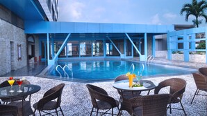 A pool area with a blue structure, outdoor seating, and a clear sky. - Nanyang Seascape (Zhuhai)