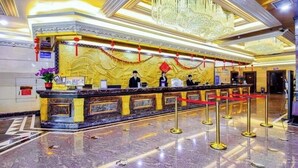 A hotel reception area with a marble counter, red ropes, and a chandelier. - Nanyang Seascape (Zhuhai)