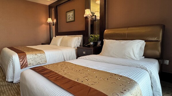 A hotel room with two beds, a nightstand with a lamp, a mirror, and a framed picture on the wall. - Nanyang Seascape (Zhuhai)