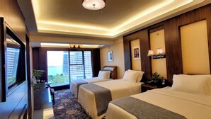 A hotel room with two beds, a TV, a desk, and a view of the city. - Nanyang Seascape (Zhuhai)