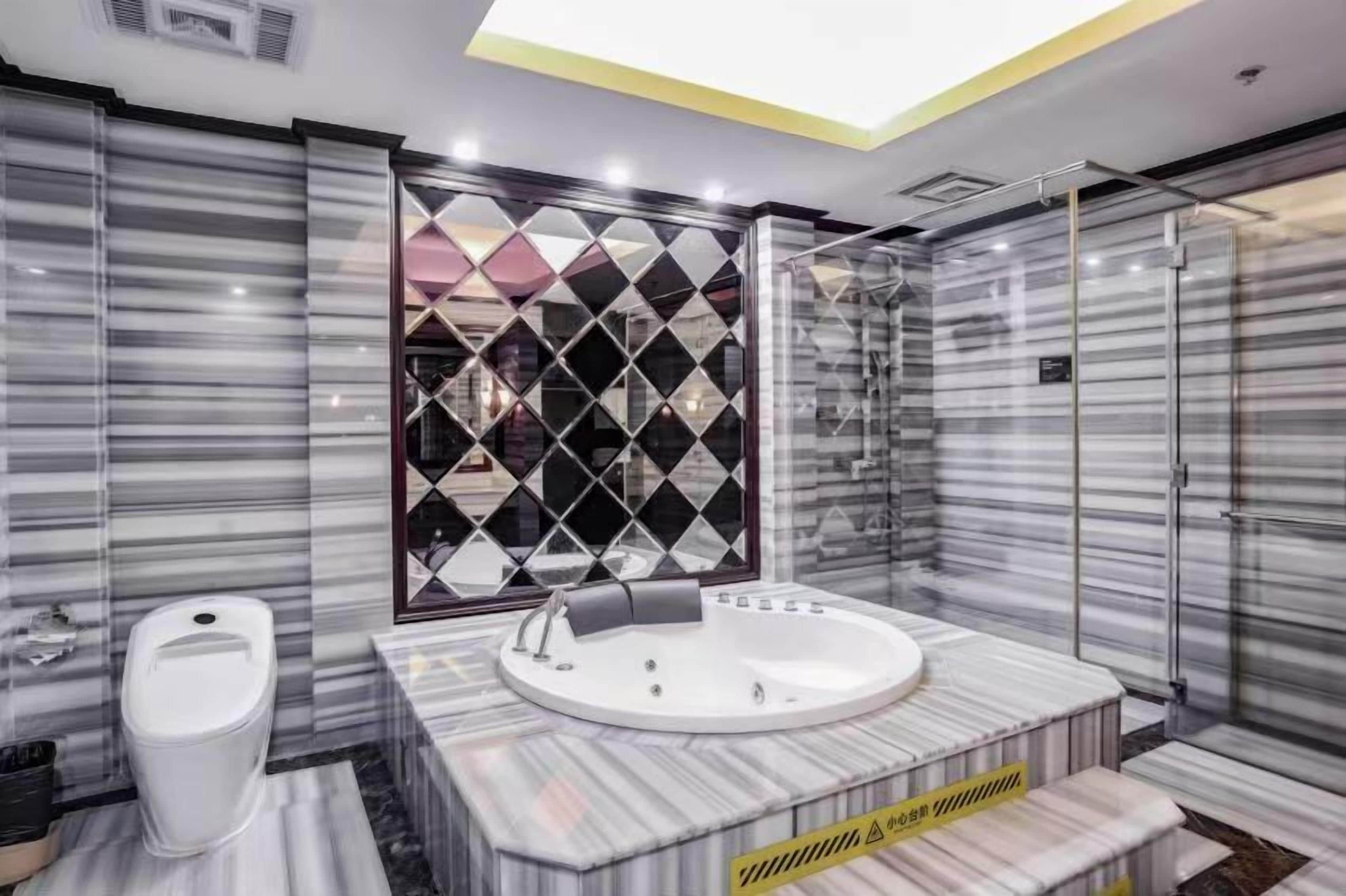 Une salle de bain moderne avec un sol en marbre, des toilettes blanches, une grande baignoire et une cabine de douche en verre.