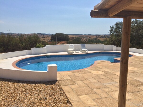 A swimming pool with a curved design, surrounded by a white wall and a wooden pergola. - Secluded 2 Bedroomed Country Cottage with Private Pool north of the Algarve (Garvao)