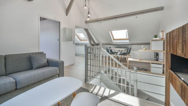 Eine moderne Lofts-Wohnung mit Schlafgalerie, Essbereich und Wohnzimmer inklusive Sofa und Couchtisch.
