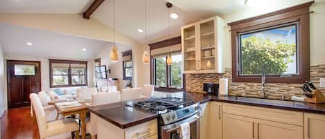 A modern kitchen with a central island, built-in cabinets, and a large window providing natural light.