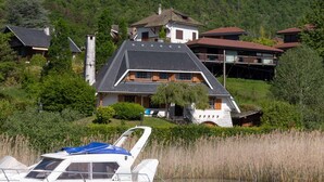 Una propiedad en una colina con varias casas, un barco amarrado cerca del agua y abundante vegetación.