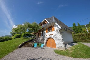 A stone house with a wooden door and a staircase leading to the entrance.