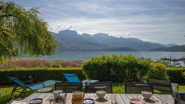 Un espacio de comedor al aire libre con vistas a montañas y un lago.