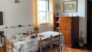 A dining area with a wooden table, chairs, and a window with curtains.