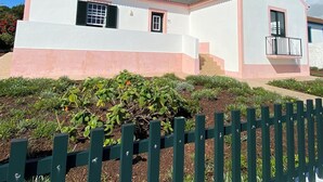 A two-story house with a pink and white exterior, a tiled roof, and a small balcony.
