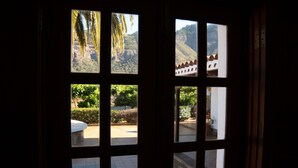 A view through a window with a stone bench and a garden.
